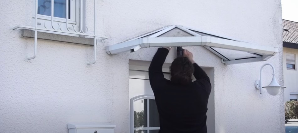 Handwerker entfernt Schrauben am alten Vordach aus Glas